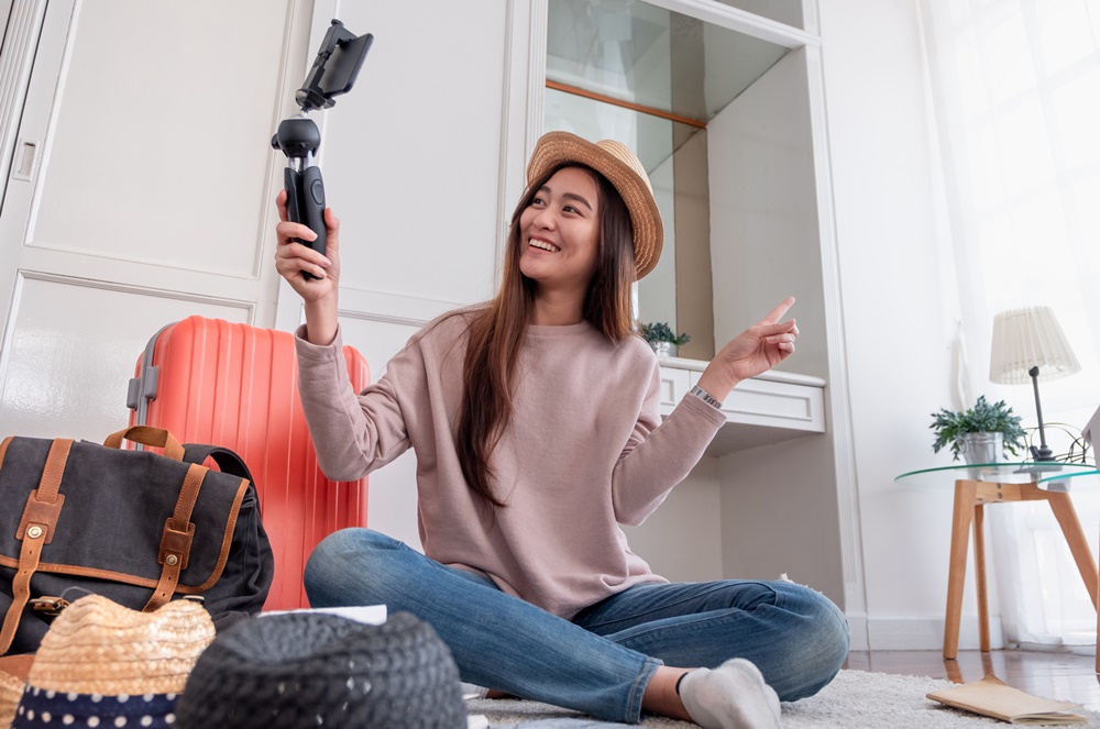 Mulher usando celular com tripé fazendo uma gravação